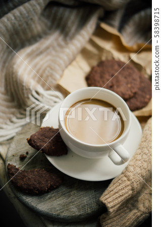 Cup of coffe with milk and chocolate cookies on warm wool blanket Cup of coffe with milk and chocolate cookies on warm wool blanket 58398715