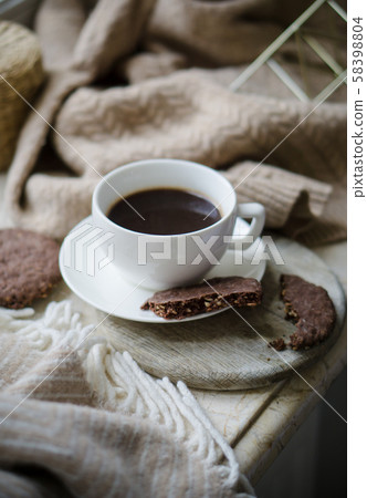 Cup of coffe with milk and chocolate cookies on warm wool blanket 58398804