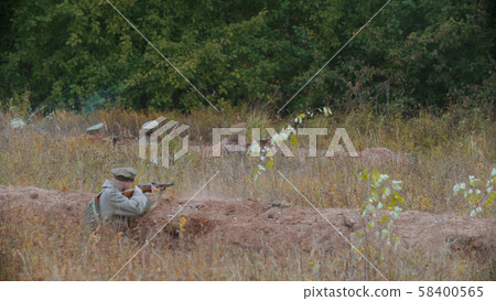 Military men in a trench are shooting on the field Military men in a trench are shooting on the field 58400565