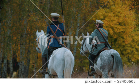 A reconstruction of military operations in Russia in 1917 - Two military men riding horses into the A reconstruction of military operations in Russia in 1917 - Two military men riding horses into the 58400603