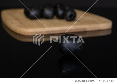 Pickled black olive isolated on black glass 58404238