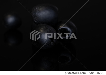 Pickled black olive isolated on black glass 58404633