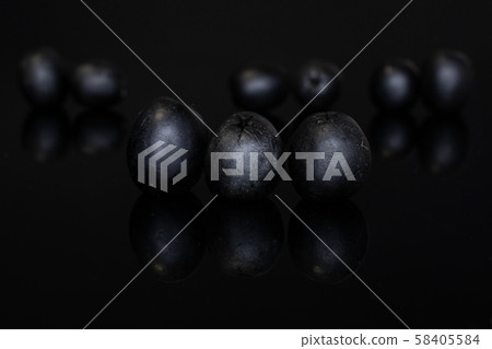 Pickled black olive isolated on black glass 58405584