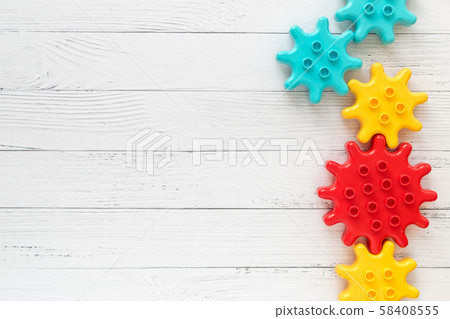 Plastic constructor gearwheels on white wooden Plastic constructor gearwheels on white wooden 58408555