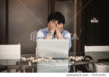 Asian depressed businessman with casual suit in seriuos action while working with computer laptop and take medicine in modern meeting room office, Business lifestyle and depress concept 58410491