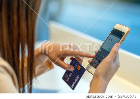 Closeup Asian woman using credit card with mobile for online shopping in department store over the clothes shop store background, technology money wallet and online payment concept, credit card mockup Closeup Asian woman using credit card with mobile for online shopping in department store over the clothes shop store background, technology money wallet and online payment concept, credit card mockup 58410575