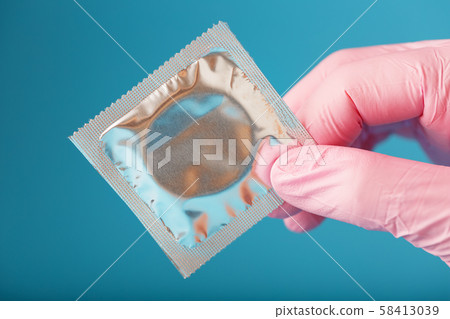 Condom contraception A hand in a pink glove holds 58413039