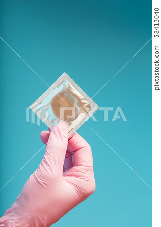 Condom contraception A hand in a pink glove holds 58413040