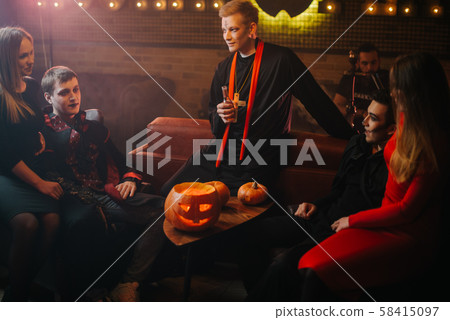 Friends in colorful festive costumes have fun at Halloween party in a cafe 58415097
