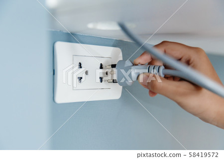 Closeup hand plug in wall socket electricity Closeup hand plug in wall socket electricity 58419572