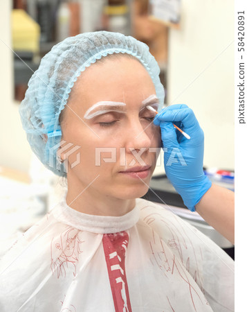 Coloring eyebrows with henna in the beauty salon. Coloring eyebrows with henna in the beauty salon. 58420891