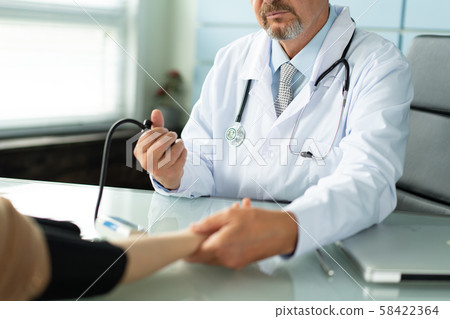 A doctor measures the blood pressure of a patient 58422364