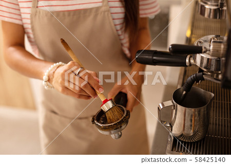 Barista using special brush while cleaning parts of coffee machine 58425140