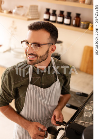 Handsome man smiling while making coffee for customer Handsome man smiling while making coffee for customer 58425269