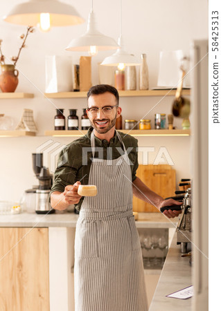 Cheerful handsome barista welcoming guests and making coffee 58425313