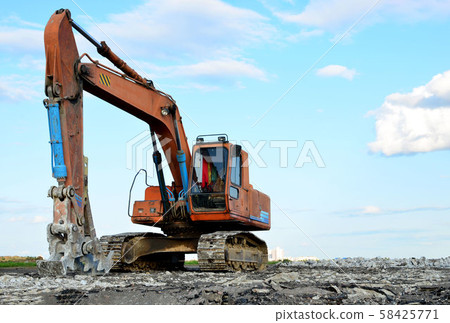 Excavator with hydraulic shears breaks asphalt on a construction site. Excavator with hydraulic shears breaks asphalt on a construction site. 58425771
