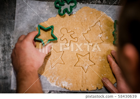 male hands cut out gingerbread cookie in the form 58430639