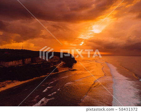 Aerial view of coastline, ocean with waves and warm sunset or sunrise.  58431372