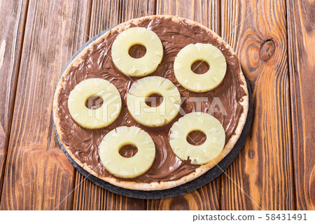 Fruit pizza with nut nougat cream and pineapple Fruit pizza with nut nougat cream and pineapple 58431491