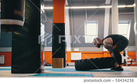 Tattooed big powerlifter is raising a big tire Tattooed big powerlifter is raising a big tire 58434238