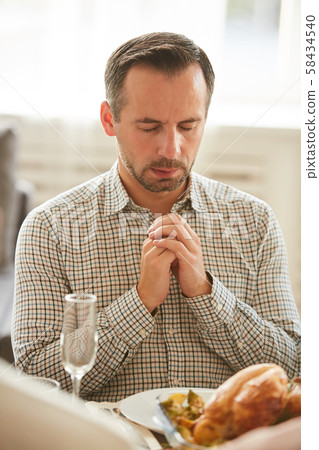 Man praying at the table 58434540