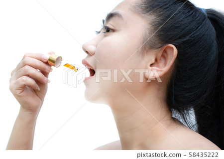 Woman holding a dropper sublingual Cannabis oil at white background 58435222