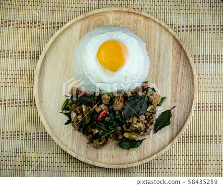 Rice topped spicy fried pork with basil leaves topping Fried Eggs on wooden dish, Pad Kra pow Moo is traditional Thai food 58435259