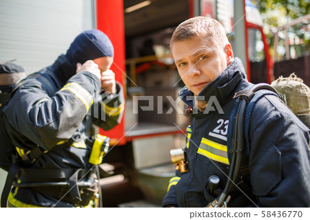 Two men firefighters standing near fire engine in afternoon, 58436770