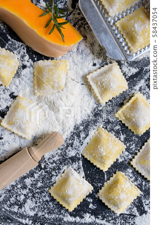 traditional raw ravioli with pumpkin on a wooden table with flour, handmade, cooking process 58437054