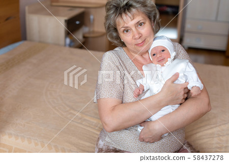 Baby boy in grandmother's arms at home 58437278
