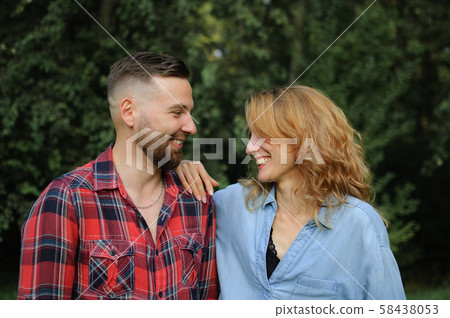 Girlfriend wearing blue casual jeans blouse is looking at handsome hipster boyfriend in red shirt 58438053