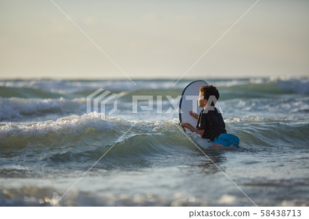 Boy breaking the waves on a surf board Boy breaking the waves on a surf board 58438713
