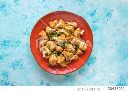 Pieces of fried cauliflower on an orange plate.  58438911