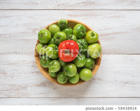 One red tomato among several green tomatoes  58438914