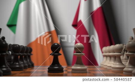 Flags of Ireland and Denmark behind pawns on the chessboard. Chess game or political rivalry related Flags of Ireland and Denmark behind pawns on the chessboard. Chess game or political rivalry related 58440587