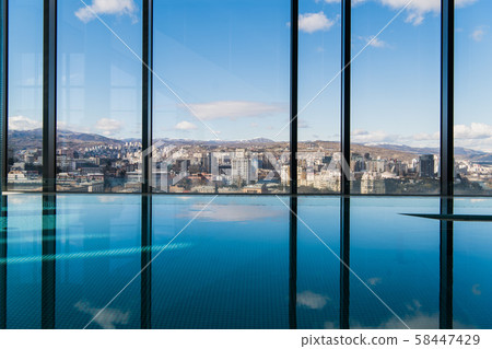 Contemporary interior with swimming pool and city view. Great water surface 58447429