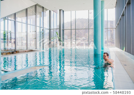 Shot of a handsome young happy man in the indoor swimming pool Shot of a handsome young happy man in the indoor swimming pool 58448193