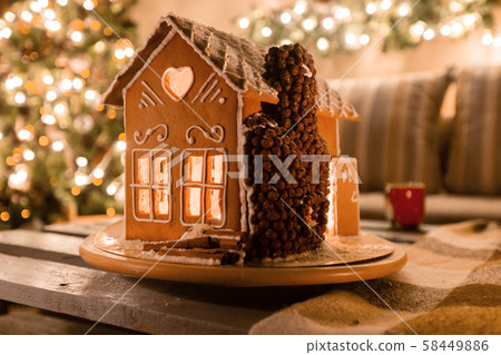 Christmas eve in the living room.. Homemade gingerbread house on background room decorated for 58449886