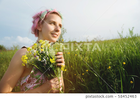 Portrait of a young happy smiling girl in a cotton dress with a bouquet of wildflowers Portrait of a young happy smiling girl in a cotton dress with a bouquet of wildflowers 58452463