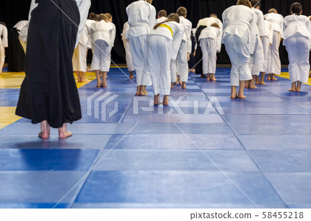 People in kimono warming up on tatami on martial arts training seminar People in kimono warming up on tatami on martial arts training seminar 58455218