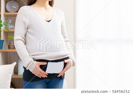 Pregnant woman putting disposable warmers on stomach Pregnant woman putting disposable warmers on stomach 58456252