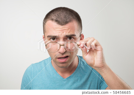 Wow facial emotion concept. Surprised young man with opened mouth touching glasses. Wow facial emotion concept. Surprised young man with opened mouth touching glasses. 58456685