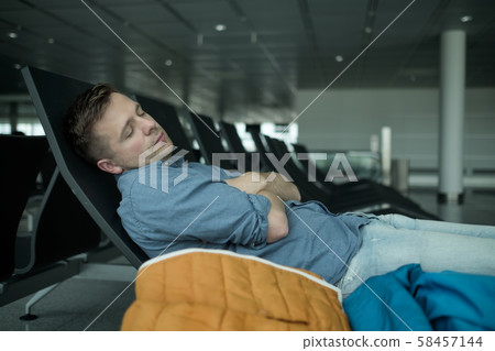 Mature man in airport sleeping on a bench Mature man in airport sleeping on a bench 58457144