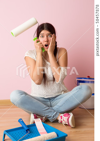 Woman with paint roller sitting on the floor Woman with paint roller sitting on the floor 58457878