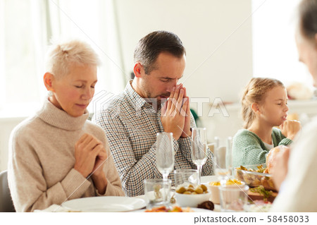 Family praying at the dining table Family praying at the dining table 58458033