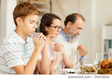 Young boy praying before dinner Young boy praying before dinner 58458038