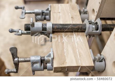 Using clamps and glue to connect wooden timbers for furniture detail. 58460072