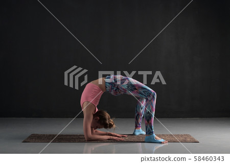 woman doing asana chakrasana or urdva dhanurasana or wheel pose. Hard variation. 58460343