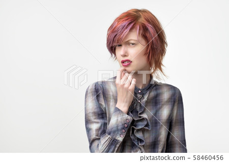 Portrait of unusual informal pretty woman with colorful hairstyle has a disgust expression on face. 58460456