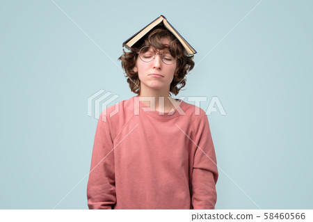 Young student in pin kpullover with book over head 58460566